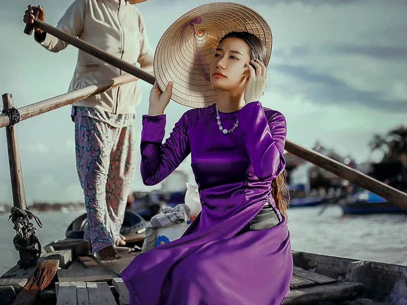 Jeune femme en áo dài violet sur une barque