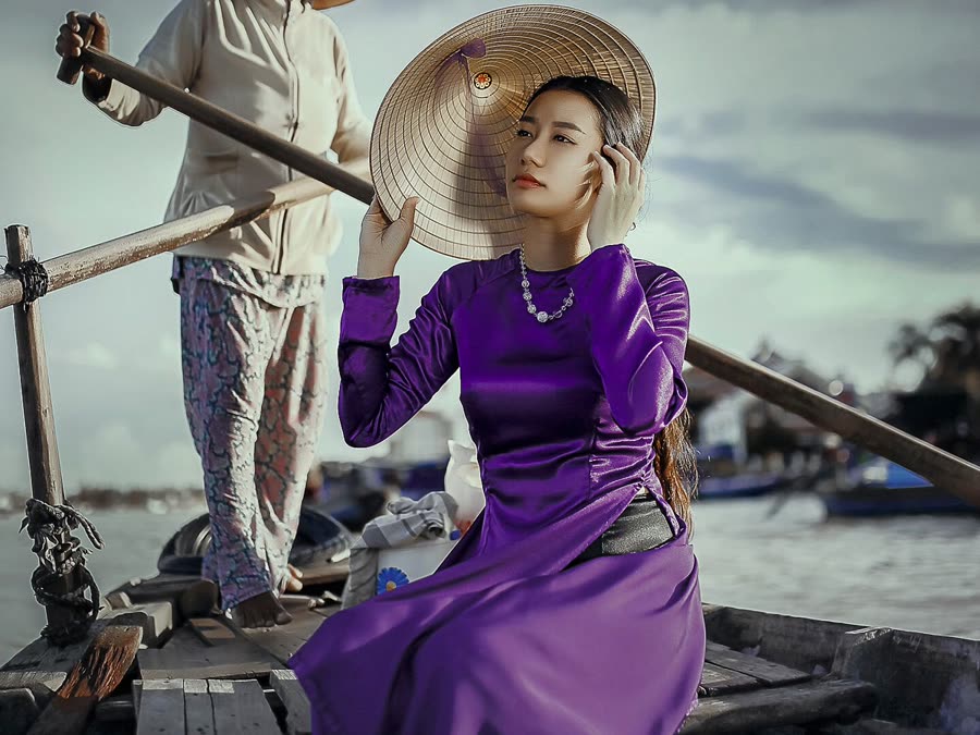 Jeune femme en áo dài violet sur une barque